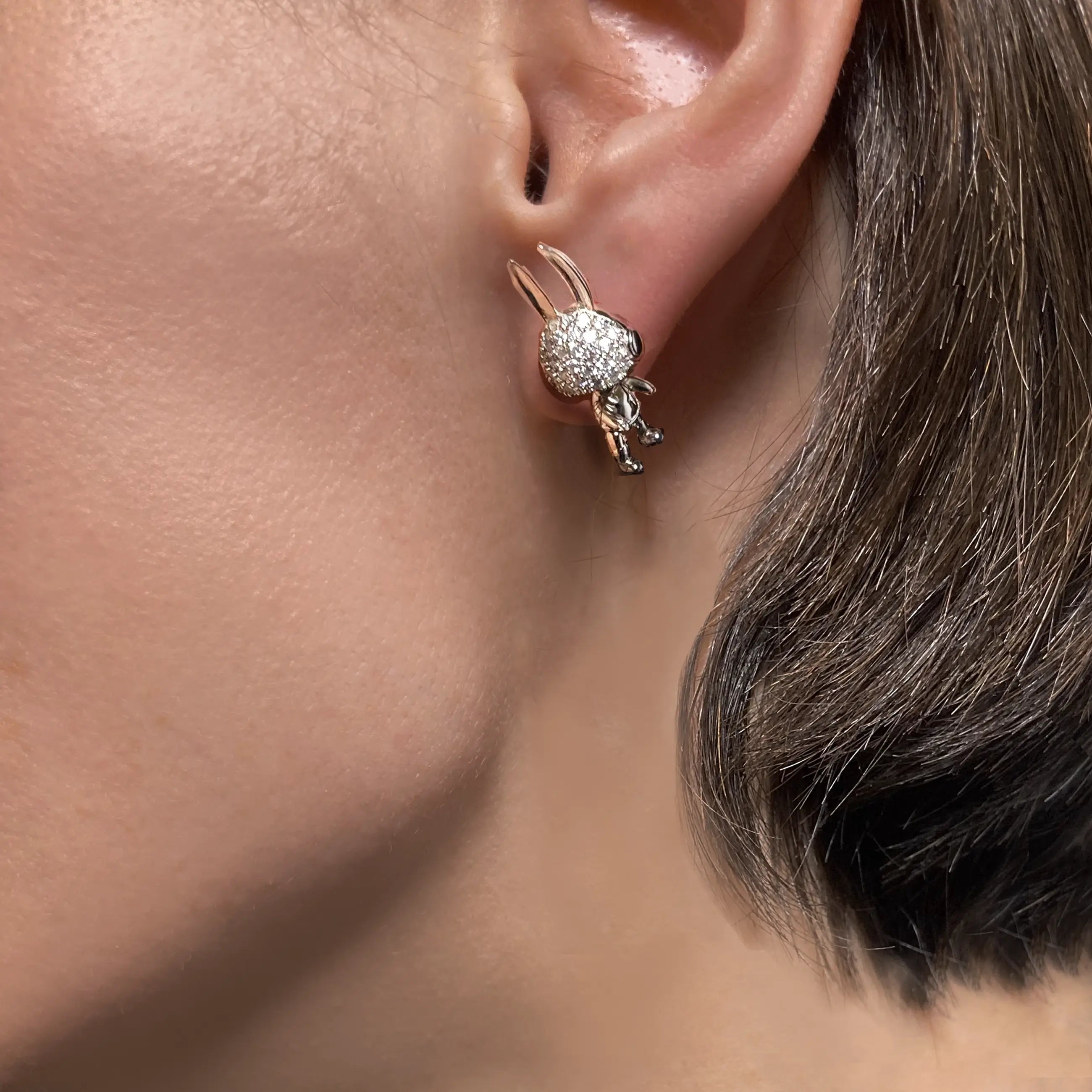 Close-up of an ear wearing a sparkling bunny earring with a blurred background